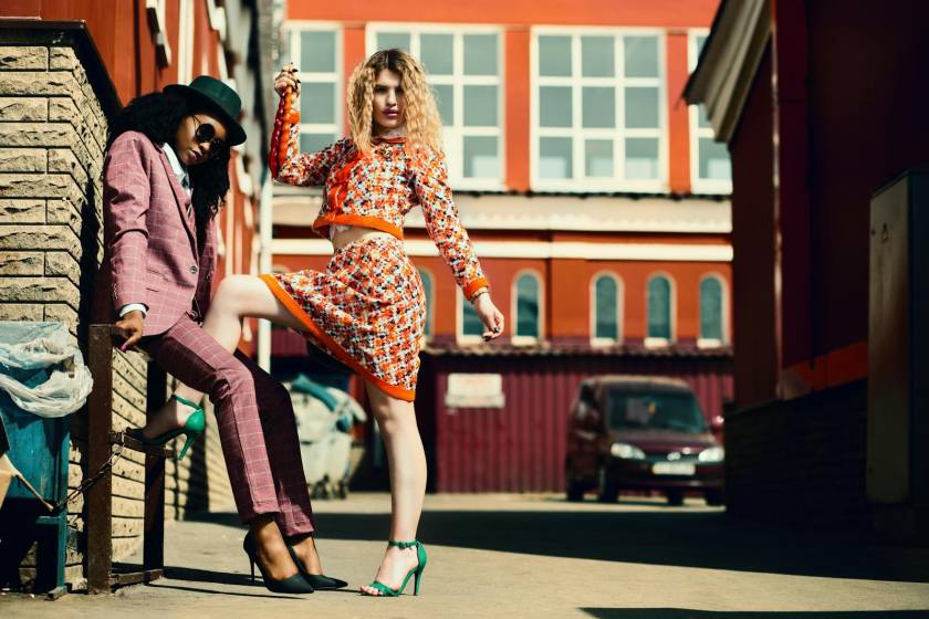 Stylish women posing in an urban alley showcasing contemporary fashion trends.
